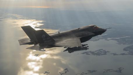 Futuristic Fighter Jet in Action Above Waterway wallpaper