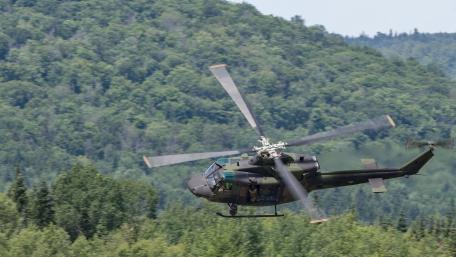 Military Helicopter in Flight Over Lush Green Landscape wallpaper