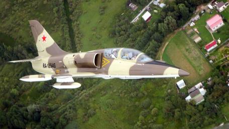 Sleek Military Aircraft in Flight Over Green Fields wallpaper