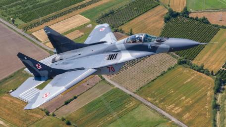 Mighty Fighter Jet Soaring Above Fields wallpaper