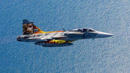 Bold Fighter Jet Soars Over Ocean Waves wallpaper