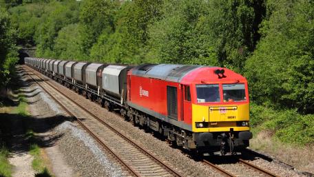 Vibrant Red Locomotive in Motion Over Green Landscape wallpaper