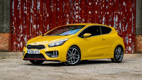 Vibrant Yellow Hatchback Against Rustic Background wallpaper