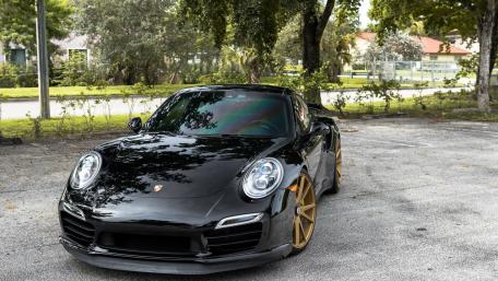 Sleek Black Porsche with Striking Gold Rims Awaits Adventure wallpaper