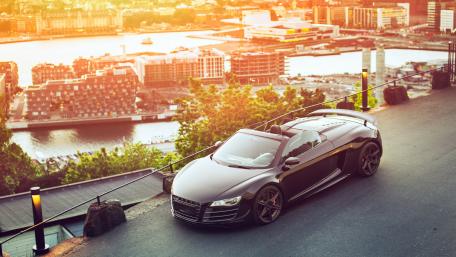 Sleek Luxury Car Overlooking Sunset Cityscape wallpaper
