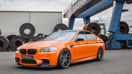 Dynamic Orange BMW M5 in Industrial Setting wallpaper
