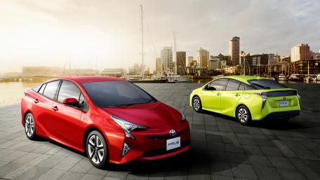 Dynamic Toyota Prius Duo Against Urban Skyline wallpaper