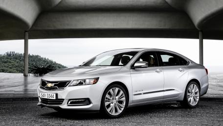 Sleek Silver Sedan Under Modern Architectural Design wallpaper