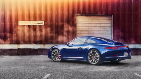 Sleek Blue Sports Car Against a Vibrant Sunset Background wallpaper
