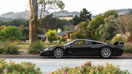 Sleek Black Supercar on Scenic Roadway wallpaper