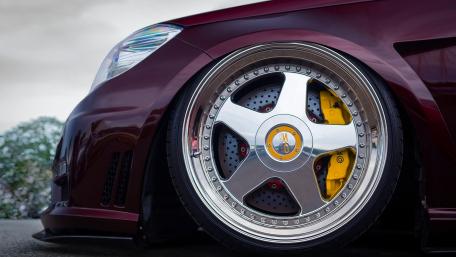 Sleek Maroon Car with Stunning Wheels and Brakes wallpaper