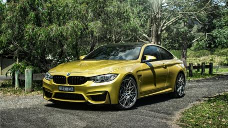 Sleek Golden BMW M4 on a Scenic Roadway wallpaper