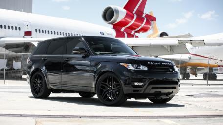 Sleek Black SUV Against a Bold Aviation Backdrop wallpaper