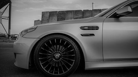 Sleek Silver Car with Striking Black Wheels and Industrial Background wallpaper