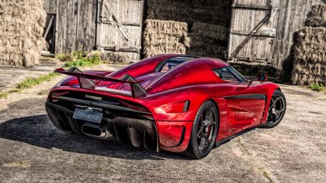 Sleek Red Hypercar in a Rustic Setting wallpaper