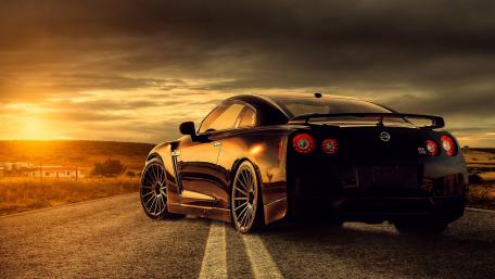 Sleek Black Sports Car Against a Dramatic Sunset wallpaper