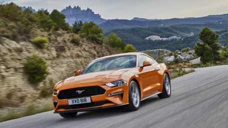 Vibrant Orange Mustang on Scenic Road wallpaper