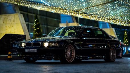 Sleek Black Luxury Car Under Twinkling Lights wallpaper