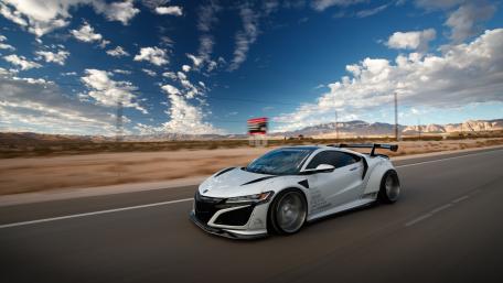 Sleek White Sports Car Racing Through Desert Landscape wallpaper