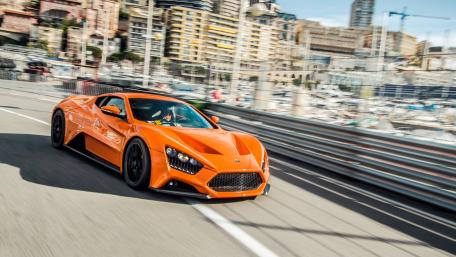 Dynamic Orange Supercar on a Coastal Roadway wallpaper