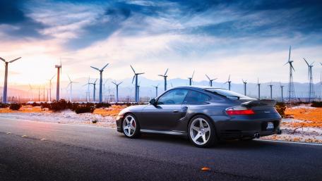 Stylish Car Against a Scenic Wind Farm Background wallpaper