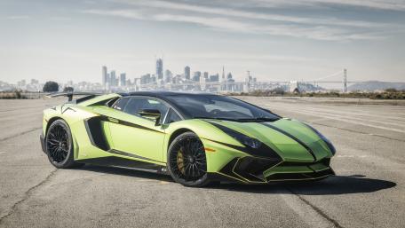Dynamic Green Sports Car Against a City Skyline wallpaper