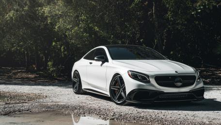 Sleek White Luxury Coupe in Nature Setting wallpaper
