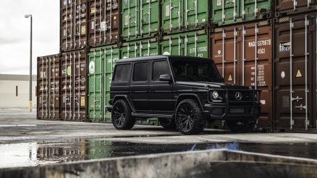 Sleek Black SUV Surrounded by Shipping Containers wallpaper