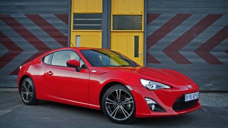 Sleek Red Sportscar Against Industrial Backdrop wallpaper