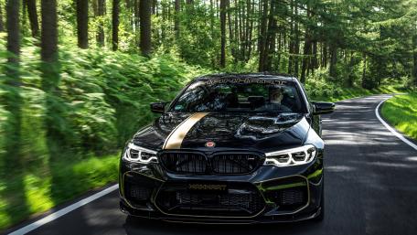 Sleek Black BMW on Lush Forest Road wallpaper