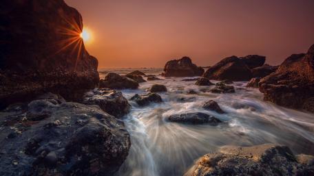 Serene Sunset Over Rocky Shoreline wallpaper