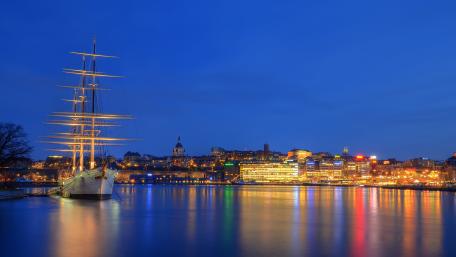 Elegant Schooner Illuminated Amidst City Lights at Night wallpaper