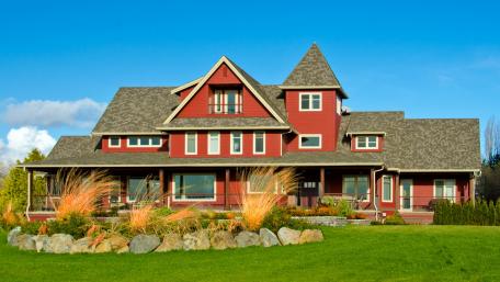 Charming Red Cottage Surrounded by Lush Lawn and Blue Sky wallpaper