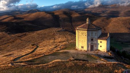 Mysterious Hilltop Sanctuary Amidst Golden Landscape wallpaper