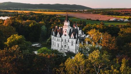 Majestic Castle Surrounded by Lush Greenery and Rolling Hills wallpaper