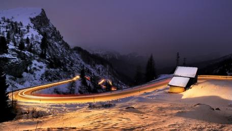 Curving Road Through Snowy Mountains at Night wallpaper