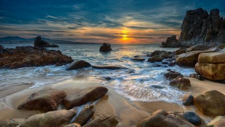 Serene Sunset Over Rocky Shoreline wallpaper
