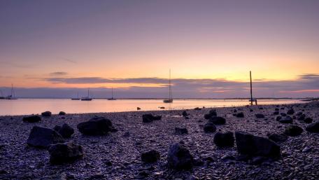 Serene Purple Sunset Over Tranquil Shoreline wallpaper