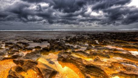 Stormy Coastal Beauty Over Rocky Shoreline wallpaper