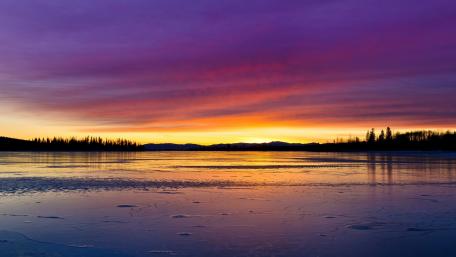 Serene Purple Sunset Over Tranquil Lake wallpaper