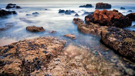 Serene Coastal Beauty Amidst Boulders and Waves wallpaper