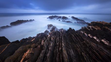 Mysterious Coastal Serenity Amidst Rocks and Waves wallpaper