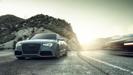 Sleek Audi Sport Car Against Scenic Mountain Road wallpaper