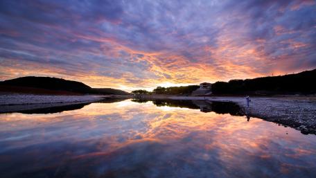 Serene Sunset Reflection Over Tranquil River wallpaper