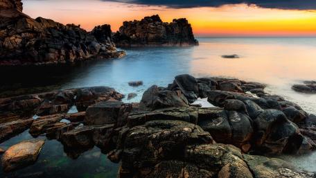 Serene Sunset Over Rocky Coastline wallpaper