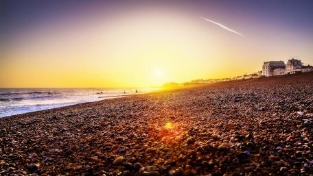 Golden Horizon Over Pebbled Beach Scene wallpaper