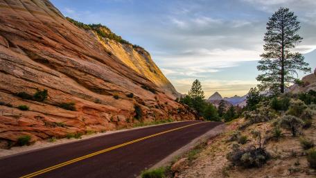 Stunning Desert Road Surrounded by Majestic Mountains wallpaper