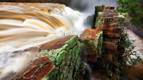Majestic Waterfall Amidst Rocky Landscapes wallpaper