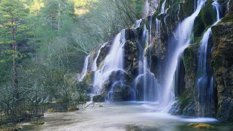 Tranquil Waterfall Amidst Lush Greenery wallpaper