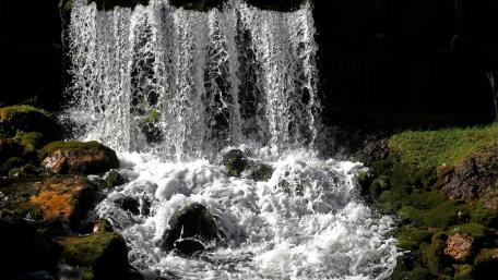 Serene Waterfall Cascading Over Mossy Rocks wallpaper